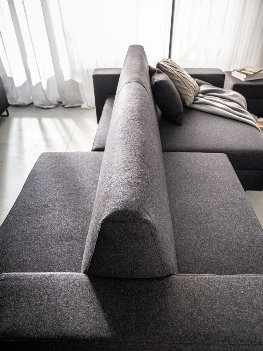 Ciemnoszara sofa z wysokim zagłówkiem w nowoczesnym salonie